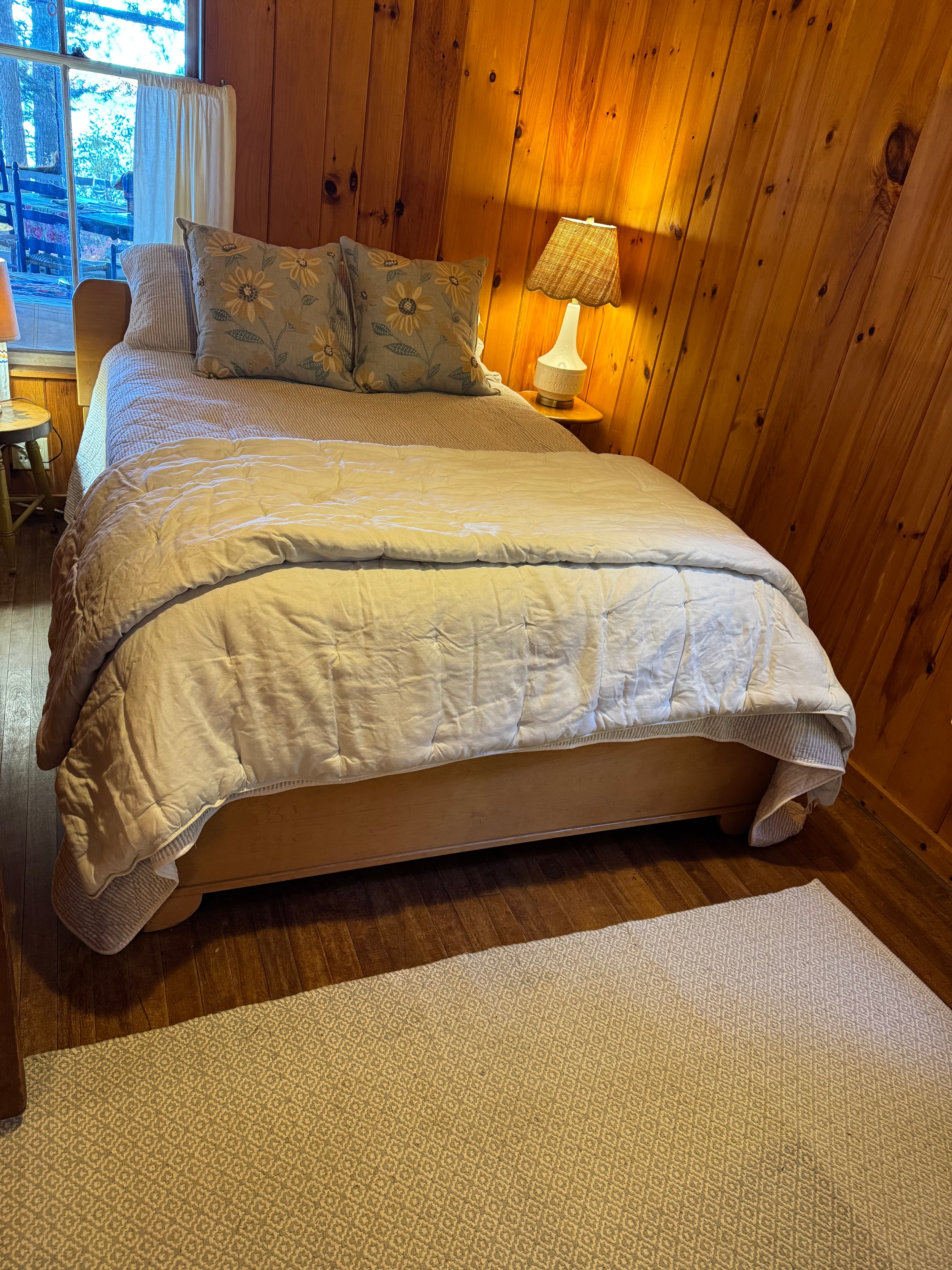 Lake camp bedroom after staging — bed with floral pillows and patterned wallpaper